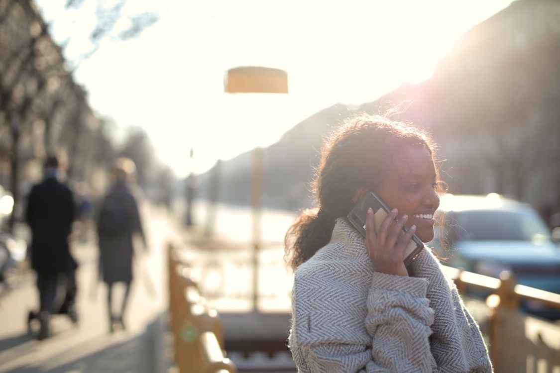 Smiling woman talking on her phone in bright sunlight